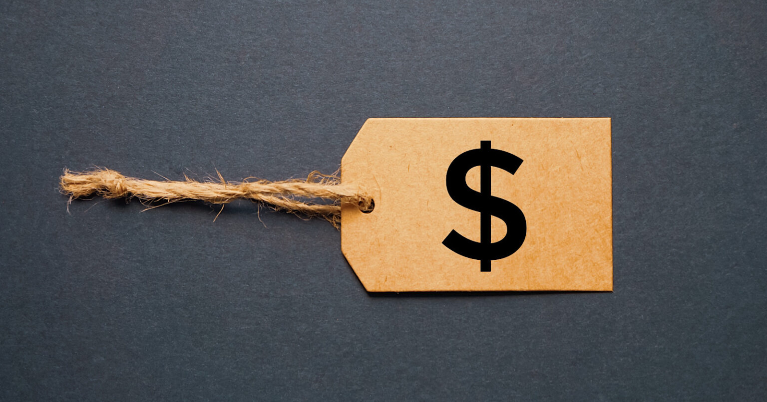 A brown cardboard price tag with a twine string and a black dollar sign symbol, influenced by the Link Tax Law, set against a dark gray background.